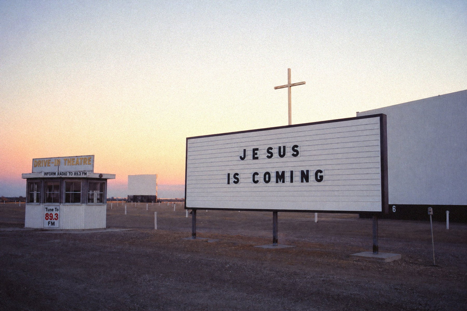 Drive-in theater at dusk, marquee reading JESUS IS COMING